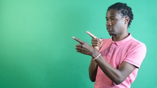 Sağ köşeyi gösteren siyah genç, ekranın sağ tarafını iki eliyle gösteriyor, yeşil ekranın önünde vücut dilini ve yüz ifadelerini gösteriyor. - Video, Çekim