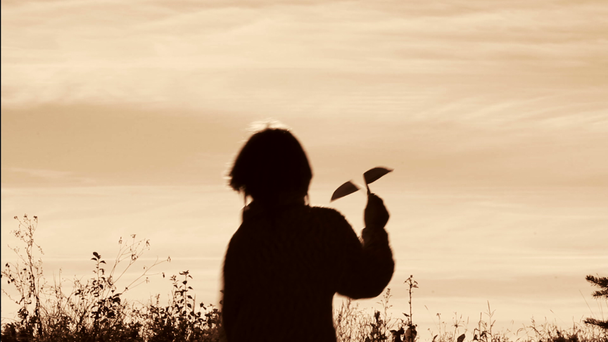Silhouette eines Jungen, der mit einem Papierflugzeug spielt.lonely boy playing outdoors.the child starts plane on sky background.black and white, retro, sepia. - Filmmaterial, Video