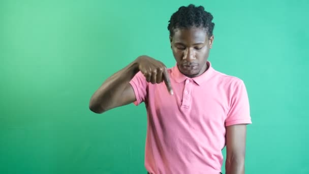 Zwarte man wijzend vinger naar beneden, jonge zwarte man wijzend naar de onderkant van het scherm met zijn linkerhand, toon lichaamstaal en gezichtsuitdrukkingen voor een groen scherm - Video