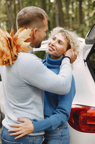 Blonde curly woman and man hugging. Couple wearing blue sweaters. Photo of romantic couple with a dried leaves. - Fotografie, Obrázek