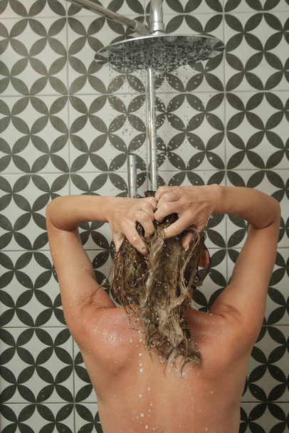 Young woman taking shower and washing her hair in shower cabine. - Photo, image