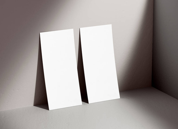Két DL függőleges szórólap mockup üres papír támaszkodik a falon a tervezési bemutató. Fehér üres szórólap sablon árnyékokkal a háttérben 3D illusztráció. Levélpapír-koncepció - Fotó, kép