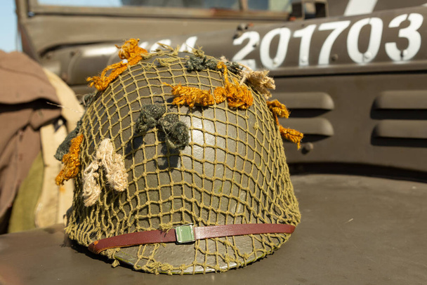 An M1 US infantry helmet from the Second World War lies on the bonnet of a military vehicle. - Foto, afbeelding