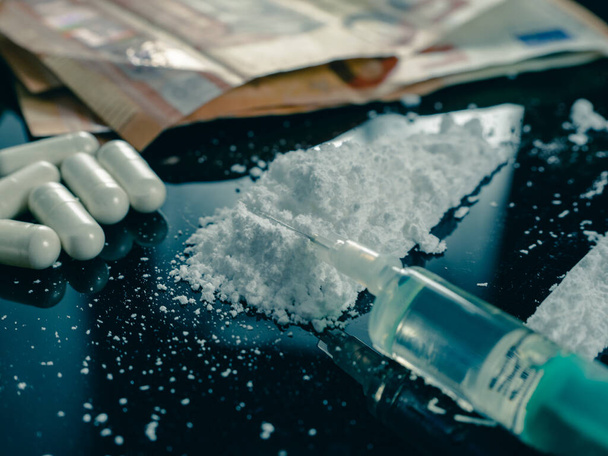 Money and drugs on a black glass table. Money, syringe and drugs. - Foto, Imagem