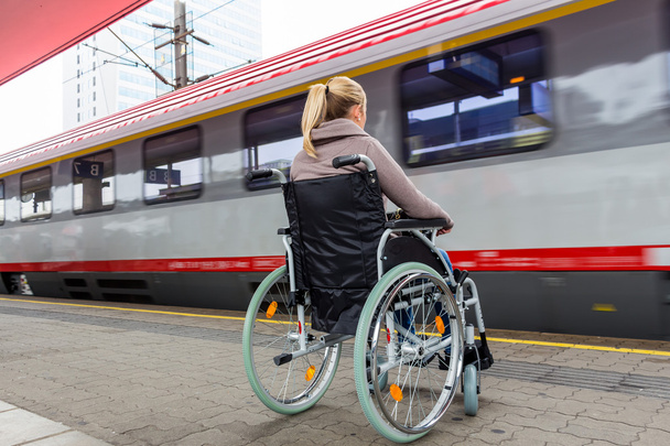 woman sitting in a wheelchair on a train station - Foto, afbeelding
