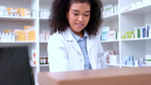 Happy black pharmacist answering a phone in a pharmacy, checking stock, doing inventory and assisting patients with their prescriptions. Modern no contact dispensary with a health care professional. - Filmati, video