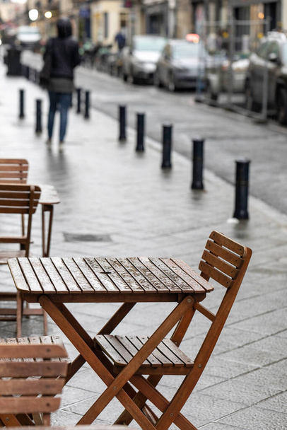 An empty outdoor area of a traditional french restaurant or cafe in a historic downtown. Tables and chairs without visitors.  Business in HoReCa. A rain droplets on table. - Valokuva, kuva