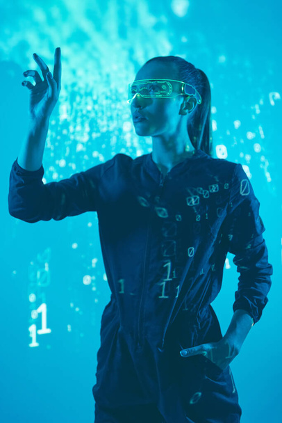 Confident young woman in futuristic glasses gesturing against colorful background - Fotografie, Obrázek