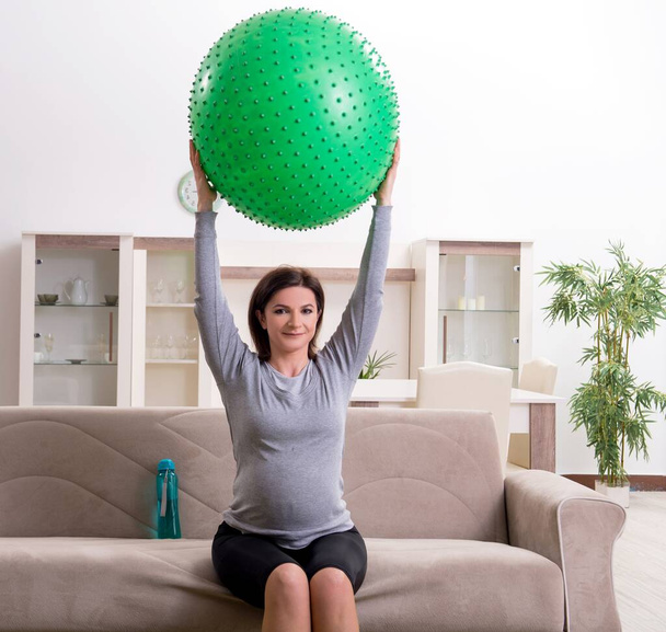 Беременная женщина в возрасте делает упражнения дома
 - Фото, изображение