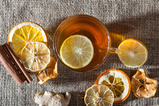 Ginger tea with spices, honey, cinnamon, lemon and dried fruit on a linen background - Fotografie, Obrázek