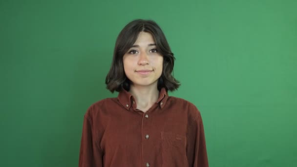 Pretty girl facial expression, pointing to the top of the screen with her fingers, facial expression of young woman in front of green curtain - Video