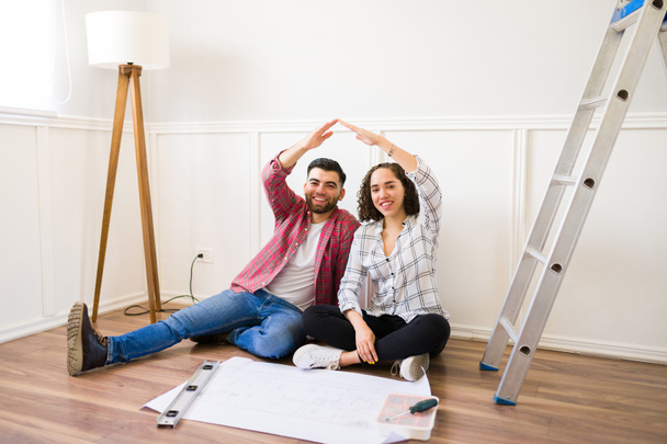 Portrait of an excited woman and man smiling while doing home improvements and renovations in their new house - Photo, image
