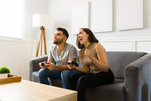 Захоплена жінка сміється і відчуває себе щасливою, граючи відеоігри зі своїм партнером у вітальні
  - Фото, зображення