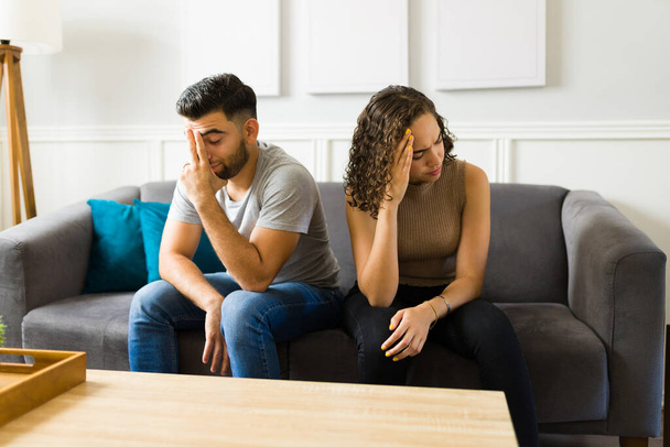 Upset young couple arguing and fighting because of communication or relationship problems while sitting on the sofa - Fotoğraf, Görsel