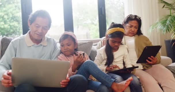 Asian children and grandparents addicted to modern technology while sitting on sofa. Multi generation family using wireless devices while bonding. Kids teaching grandfather how to use internet. - Footage, Video