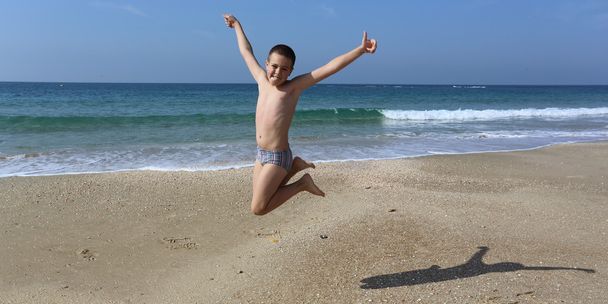 Chłopiec skacze na plaży nad morzem - Zdjęcie, obraz