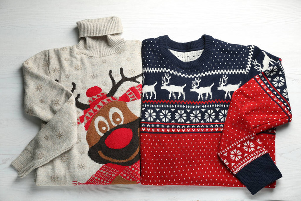 Warm Christmas sweaters on white wooden table, top view - Fotoğraf, Görsel