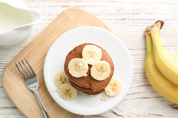 Plate of banana pancakes served on white wooden table, flat lay - Photo, Image