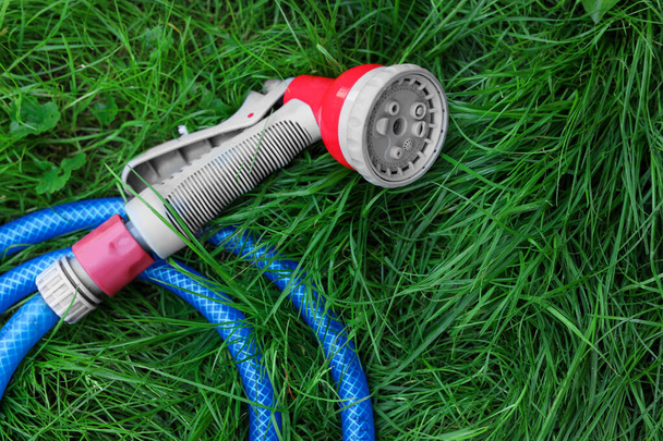 Watering hose with sprinkler on green grass outdoors, top view - Foto, imagen