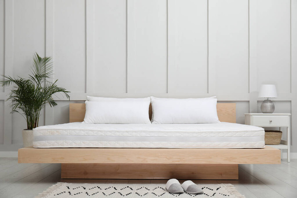 Wooden bed with soft white mattress and pillows in cozy room interior - Fotografie, Obrázek
