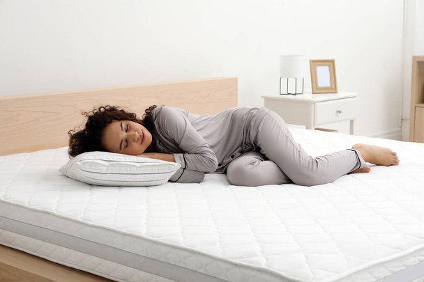 Young African American woman sleeping on bed with comfortable mattress and pillow at home - Photo, image