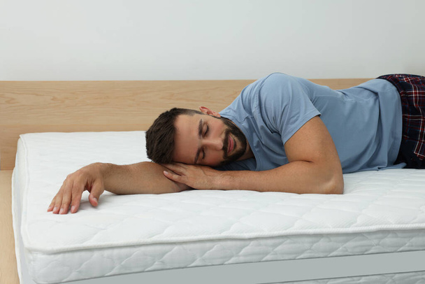 Man sleeping on bed with comfortable mattress at home - Foto, Bild