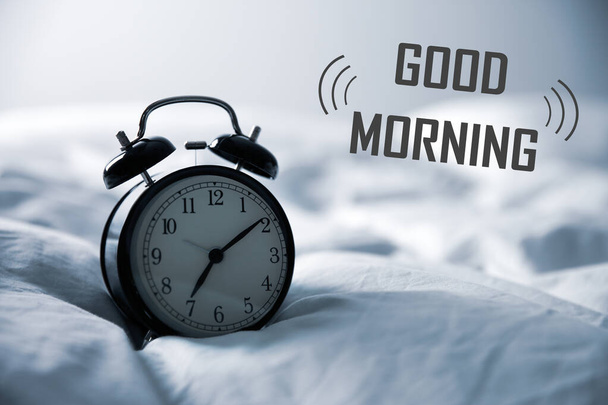 Good Morning! Black alarm clock on bed - Foto, imagen