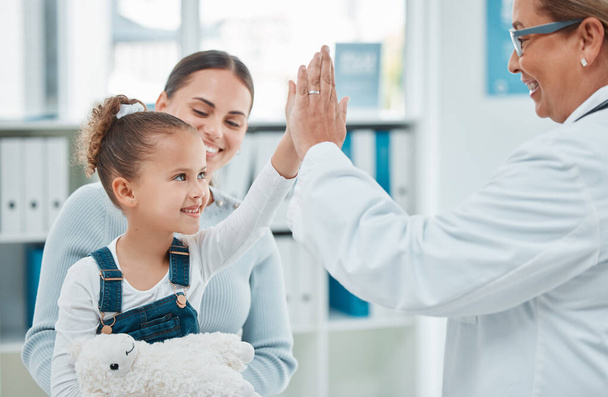 Theres nothing to be scared of. a little girl giving a doctor a high five in a clinic - Foto, afbeelding
