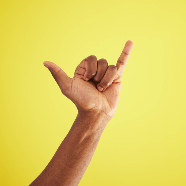 Bis bald. Studioaufnahme eines nicht wiedererkennbaren Mannes, der ein Shaka-Handzeichen vor gelbem Hintergrund zeigt - Foto, Bild