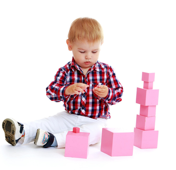Little boy collects pink pyramid. - Foto, Bild