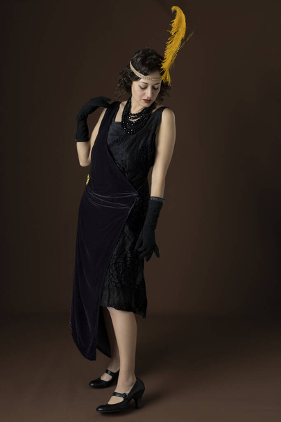 A 1920s woman wearing a party dress and a headband with a feather - Foto, immagini