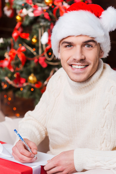 Man in Santa hat writing Christmas letter - Fotoğraf, Görsel