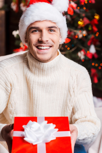 Man in Santa hat stretching out gift box - Photo, image