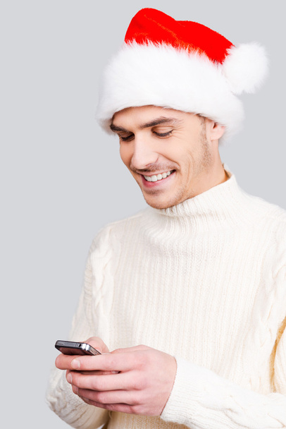 Man in Santa hat holding mobile phone - Foto, Bild