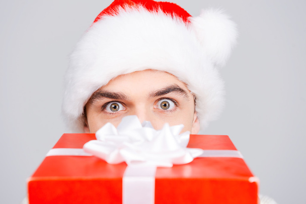 Man in Santa hat hiding face behind gift box - Foto, immagini