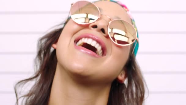 Closeup of a fashionable woman laughing and pouting with a playful expression. Portrait, headshot and face of a young, trendy and flirty lady wearing funky, stylish sunglasses while blowing kisses. - Video