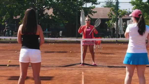Tenniscoach praat met haar studenten op de tennisbaan. Tussenschot - Video