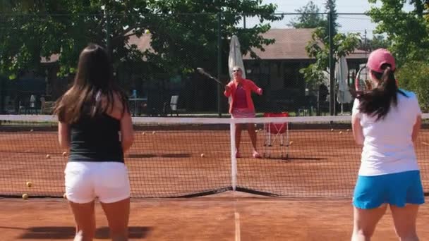 Tennis coach training her students on the tennis court. Mid shot - 映像、動画
