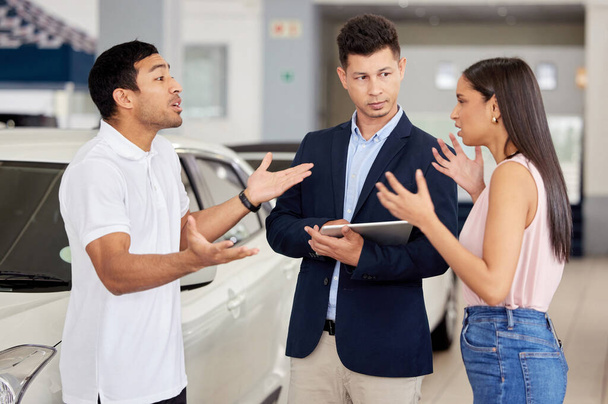 Die Entscheidung für ein Auto ist nie leicht. Ein junges Paar im Streit vor einem Autoverkäufer - Foto, Bild