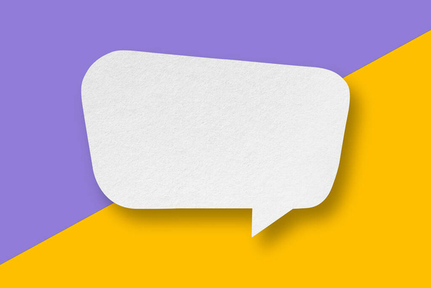 White paper cut speech balloon shape pasted on purple and yellow paper background. Design. - Photo, Image