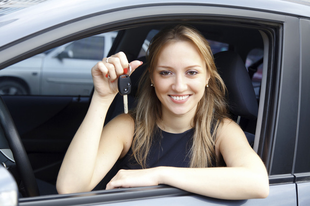 The happy woman showing the key of her new car. - Valokuva, kuva