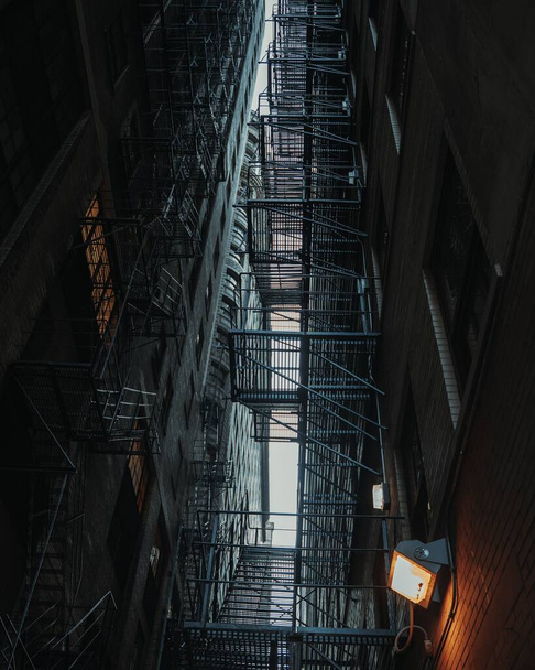 A low angle shot of fire escape stairs between the buildings - 写真・画像