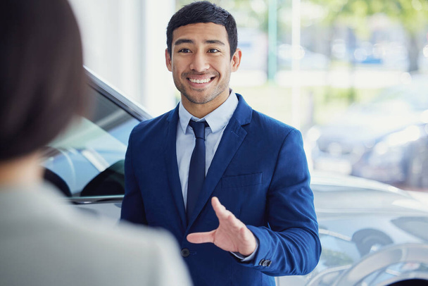 What can I do for you today. a handsome young male car salesman talking to a female customer on the showroom floor - Photo, image