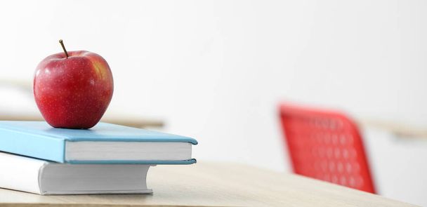 Apple and books on desk in classroom - Фото, изображение
