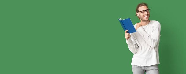 Handsome man reading book on green background with space for text - Valokuva, kuva
