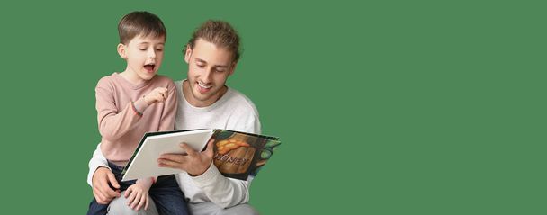 Father and his little son with book on green background with space for text - Foto, imagen