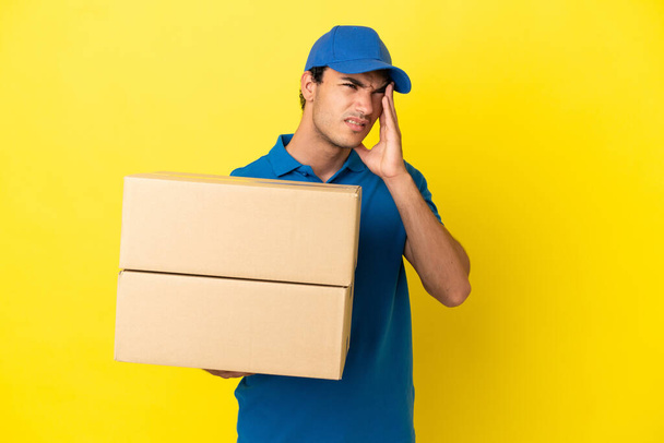 Delivery man over isolated yellow wall with headache - Foto, immagini