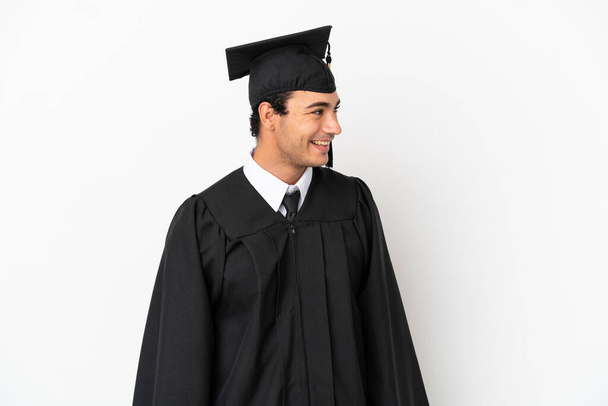 Young university graduate over isolated white background looking side - Photo, Image