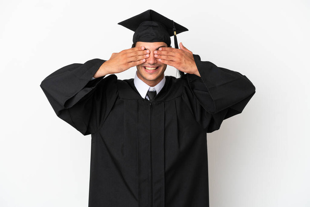 Young university graduate over isolated white background covering eyes by hands - Foto, afbeelding