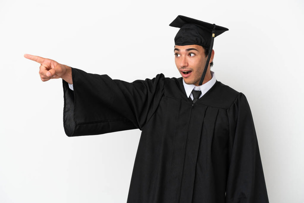Young university graduate over isolated white background pointing away - Foto, Imagem